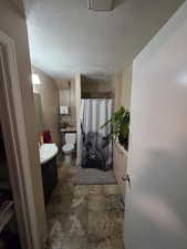Full bath with vanity, a textured ceiling, and a shower with curtain
