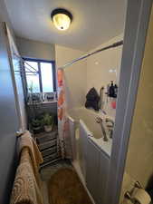 Full bath featuring a textured ceiling and shower / tub combo with curtain