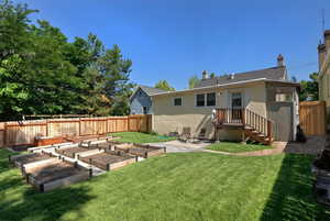 Back of house featuring a patio, a garden, a fenced backyard, a chimney, and roof with shingles