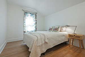 Bedroom with light wood finished floors and vaulted ceiling