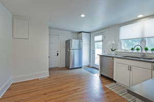 Kitchen with white cabinets, stainless steel appliances, light wood-style floors, and recessed lighting