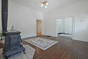 Living area with a wood stove, dark wood-style floors, and crown molding