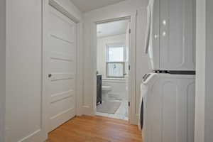 Laundry area with light wood-style floors and stacked washer and clothes dryer