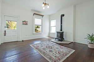 Living area with dark wood finished floors, ornamental molding, and a wood stove