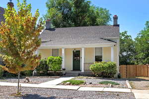 View of front of property featuring stucco siding, a porch, roof with shingles, and a chimney