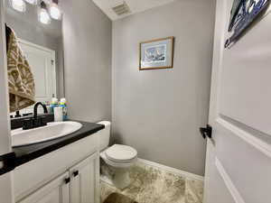 Half bath with vanity and a textured wall