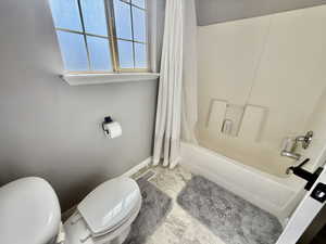 Full bath featuring toilet and shower / tub combo with curtain