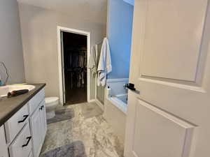 Full bathroom with a bath, vanity, a shower stall, a walk in closet, and light marble finish floors