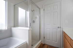 Full bath featuring vanity, a stall shower, a bath, and dark wood finished floors