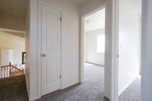 Hall with an upstairs landing and light colored carpet