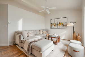 Living area featuring a ceiling fan, wood finished floors, and vaulted ceiling