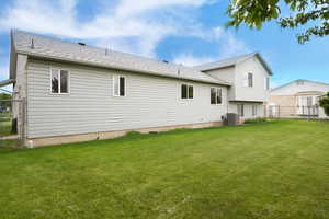 Back of house featuring a shingled roof and a gate