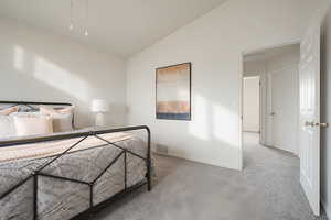Bedroom featuring light carpet and lofted ceiling
