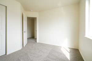 Unfurnished bedroom with light carpet and a closet