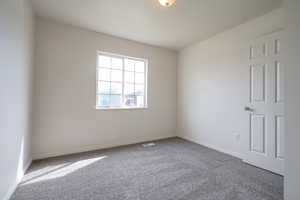 Spare room featuring carpet and baseboards