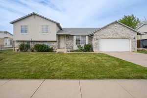 Split level home with a garage, concrete driveway, stucco siding, a shingled roof, and brick siding