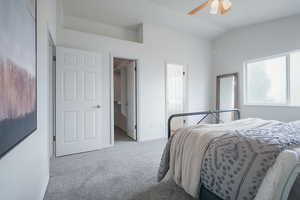 Bedroom featuring light colored carpet, a walk in closet, a ceiling fan, and lofted ceiling
