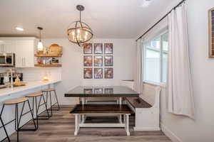 Dining space featuring dark wood-style flooring, hanging lights, and breakfast area