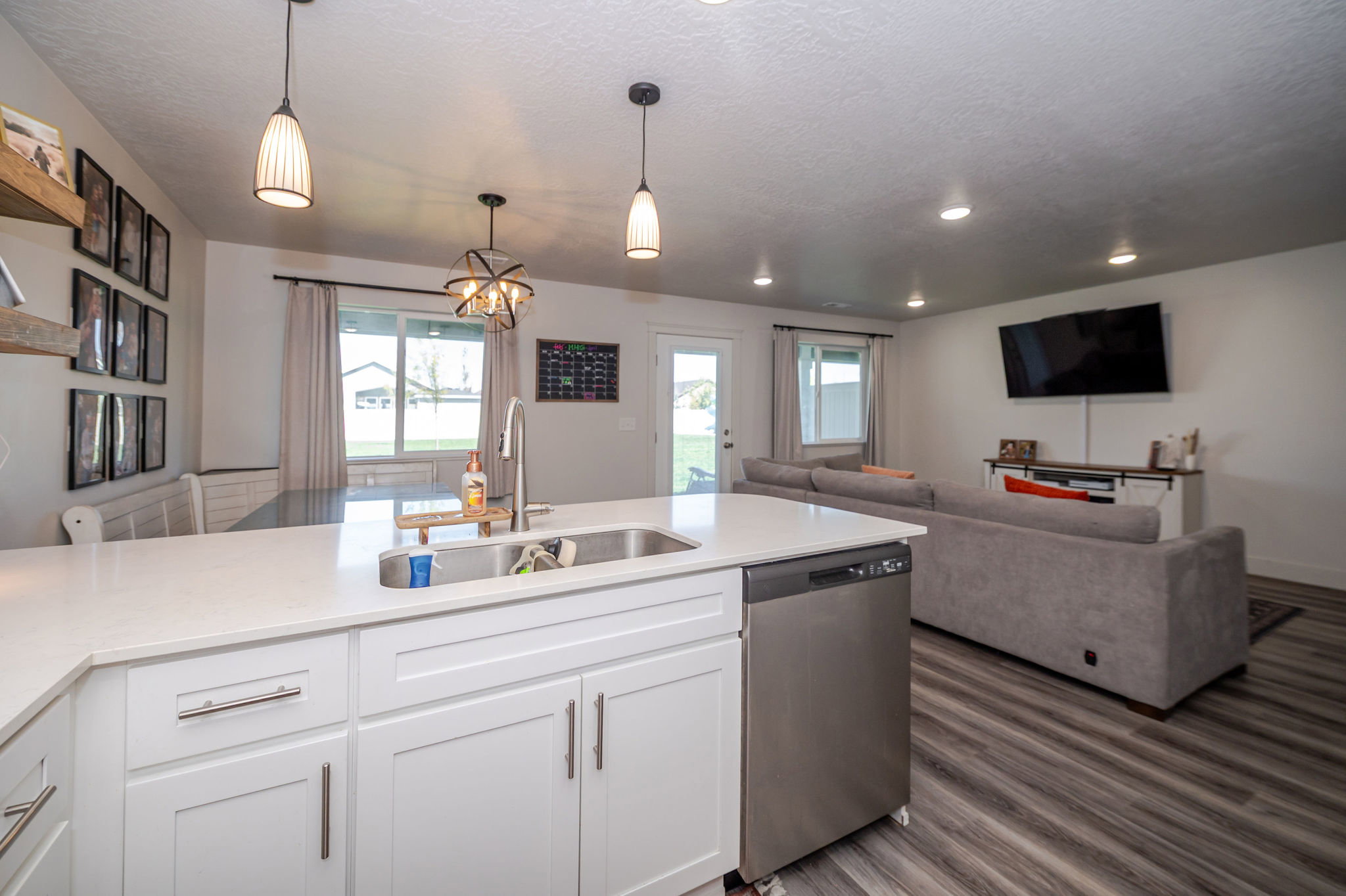 Kitchen with white cabinetry, open floor plan, dishwasher, a chandelier, and light stone counters