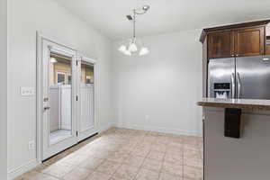 Unfurnished dining area with a chandelier and light tile patterned flooring