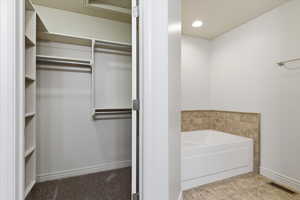 Primary Bathroom featuring a bath, a spacious closet, light tile patterned floors, and recessed lighting