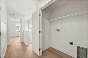 Laundry area with light wood-style floors, hookup for a washing machine, and electric dryer hookup