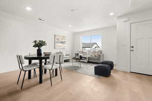 Dining room with light wood finished floors and recessed lighting