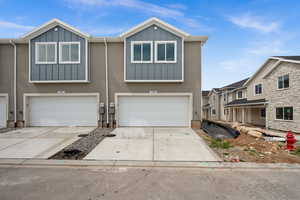 View of front of property with board and batten siding, a garage, and concrete driveway