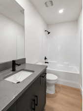 Bathroom featuring light wood-type flooring, vanity, and bathing tub / shower combination