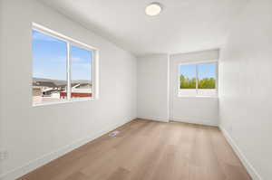 Spare room with baseboards and light wood-style floors