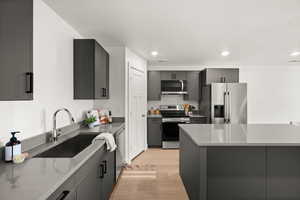 Kitchen featuring stainless steel appliances, light wood finished floors, gray cabinets, light stone counters, and recessed lighting
