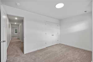Unfurnished bedroom featuring light carpet and a closet