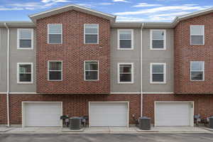 Rear view of house with a garage, stucco siding, and brick siding