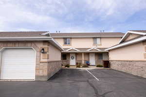 View of front of house with roof with shingles, stucco siding, a porch, and stone siding