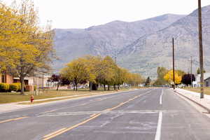 View of asphalt road with sidewalks, curbs, and a mountain view