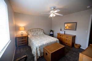 Bedroom with ceiling fan and dark colored carpet