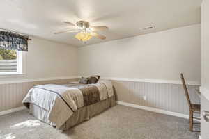 Bedroom featuring wainscoting, ceiling fan, carpet flooring, and a textured ceiling