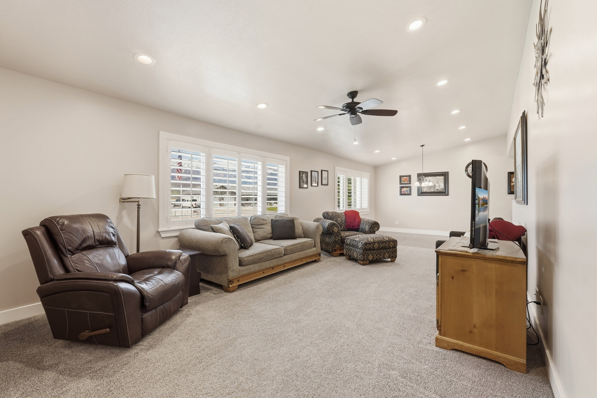 Living area featuring light colored carpet, ceiling fan, recessed lighting, and vaulted ceiling