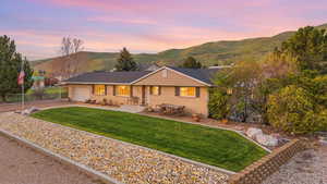 Single story home with a mountain view, a front yard, a garage, driveway, and brick siding