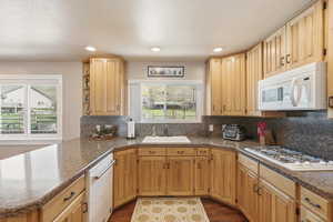 Kitchen featuring white appliances, a peninsula, recessed lighting, dark wood-type flooring, and light wood finish cabinets