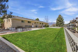 Back of property with a lawn, a patio, a mountain view, and pickleball court