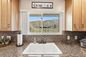 Kitchen view of light wood finish cabinetry, tasteful backsplash, and dark stone counters