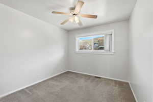 Carpeted spare room with baseboards and a ceiling fan