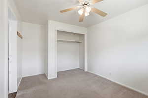 Unfurnished bedroom with light carpet, ceiling fan, and a closet