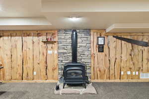 Detailed view of a textured ceiling, a gas stove, wooden walls, and carpet floors
