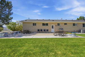 Back of property with a patio area, a lawn, and brick siding