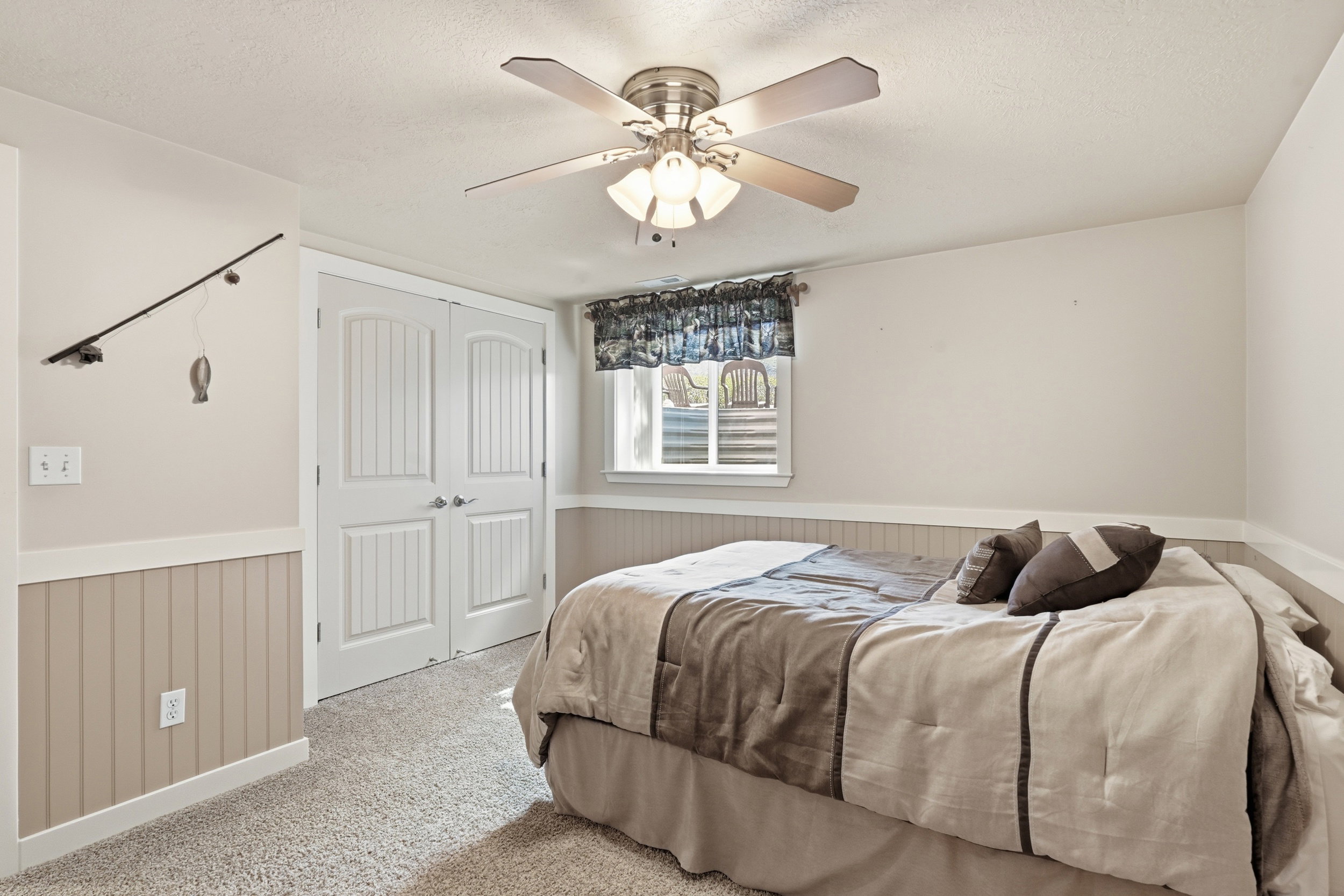 Carpeted bedroom with a wainscoted wall, a closet, ceiling fan, and a textured ceiling