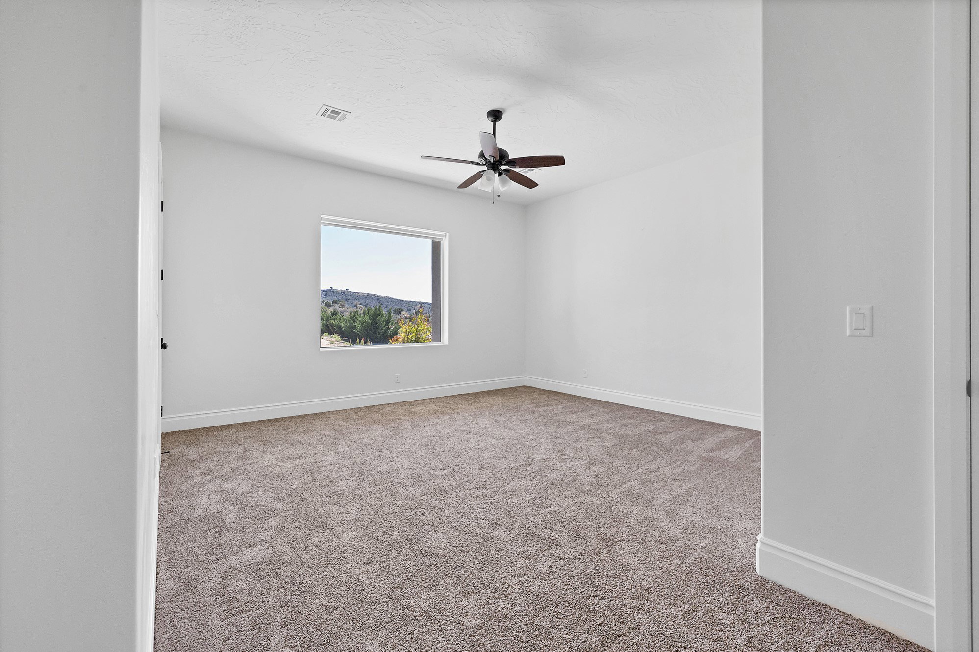 Empty room featuring light colored carpet and a ceiling fan
