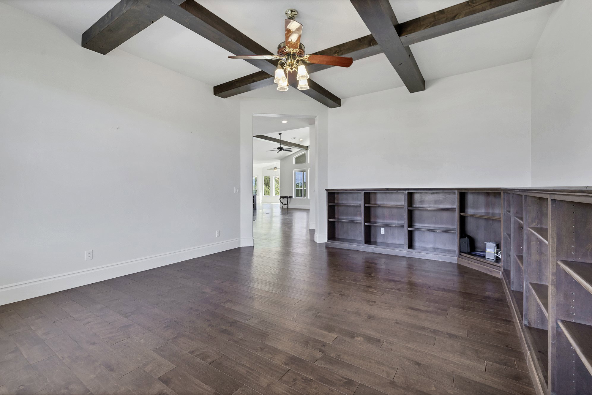 Unfurnished room featuring dark wood-style flooring, coffered ceiling, and ceiling fan