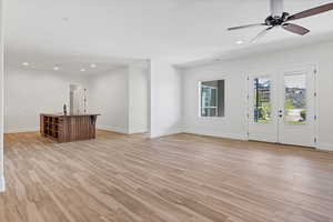 Unfurnished living room with light wood-style floors, ceiling fan, recessed lighting, and french doors